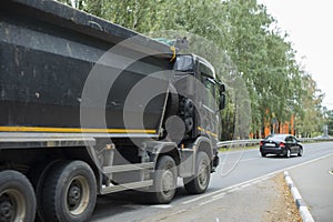 Black truck on road. Freight transport on highway. Car with body. Great trailer