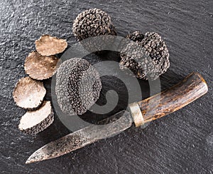 Black truffles and truffle slices on a graphite board.