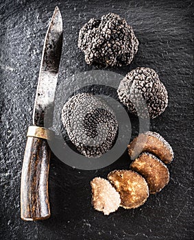 Black truffles and truffle slices on a graphite board.