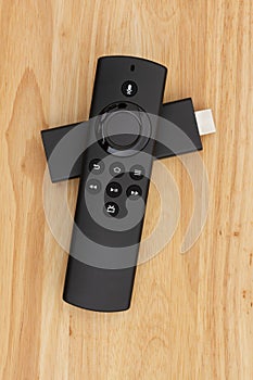 Black tv player remote with HDMI streaming device on a wood desk