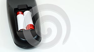 Black TV remote control with AAA alkaline batteries in red and white on a white background. Battery replacement, spare