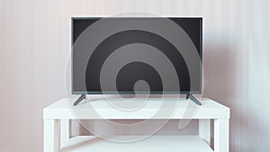 Black TV on a white stand against beige wall background