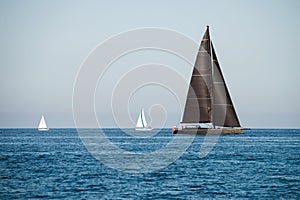 Black and two white sailing yachts on the sea