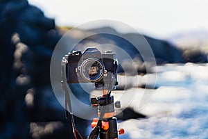 Black unbranded reflex camera planted on a tripod facing the camera