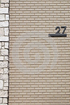 Black underlines number 27 twenty seven on tan brick with white stone border on left