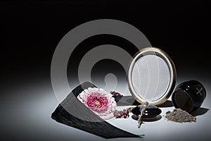 Black urn with black tape, gerbera flower, rosary for sympathy c