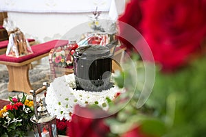 Black urn on the funeral day in church; surrounded with daisies and roses