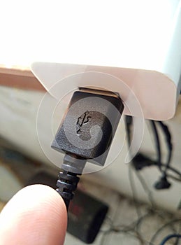 A black USB cable stuck to the adapter in a messy room