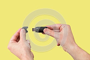 Black USB flash memory on hand with isolated yellow background