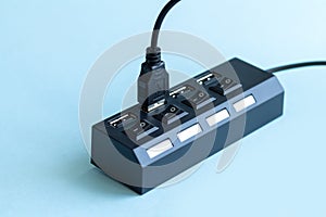 Black USB hub with usb cable plug on blue background