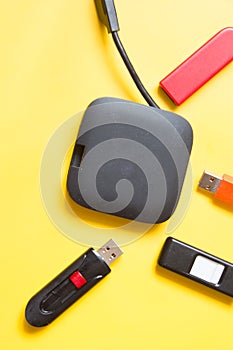 Black USB HUB with usb stick flash drives on yellow background. Top view