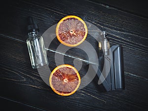 Black vaporizer in the smoke with sliced orange