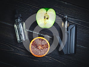 Black vaporizer in the smoke with sliced orange-apple