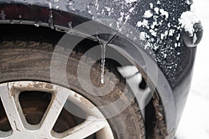 Black vehicle car covered in freezing rain, Icicles hanging from bumper. bad driving weather in freezing rain.