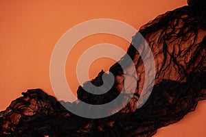 Black veil on an orange background close-up. Decorations for Halloween. Place for text, banner. The afterlife, the ghost
