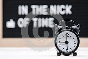 black vintage alarm clock on the background of signs with the inscription in the nick of time photo