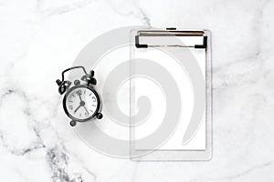 Black vintage alarm clock and blank notebook.