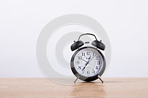 Black vintage alarm clock on thw wooden table
