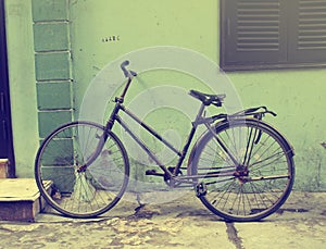 Black vintage bicycle leaning against a grunge wall