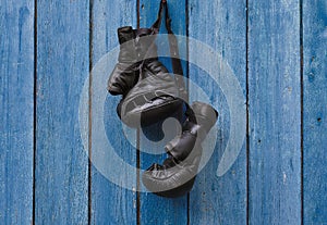 Black vintage boxing gloves hanging on an old rusty nail