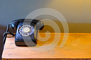 Black vintage telephone on wood desk