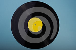 Black vinyl record with a yellow blank label for text, on a beautiful azure background.