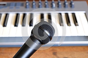 Black vocal microphone closeup against electronic synthesizer keyboard