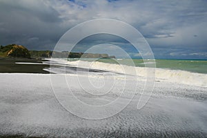 Black volcanic beach with ocean water foam, Hawke`s Bay, Napier, North Island, New Zealand