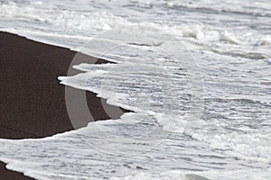 Black volcanic sand and waves on the beach in Legazpi, Philippines