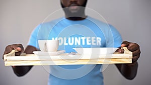 Black volunteer holding serving tray, helping patients in rehabilitation center photo