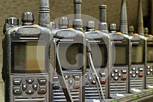 Black walkie talkies sitting on battery chargers.