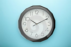 Black wall clock on the blue background