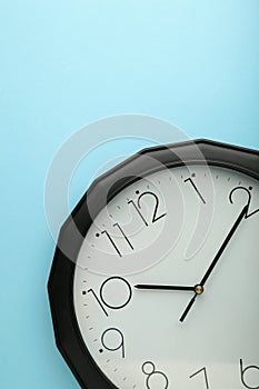 Black wall clock on the blue background