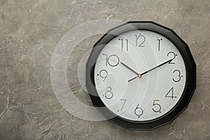 Black wall clock on the grey background
