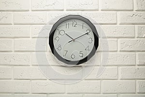 Black wall clock on the white wall background