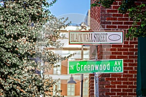 Black Wall Street and N Greenwood Avenue street signs - closeup - in Tulsa Oklahoma with bokeh background