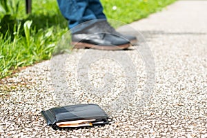 Black wallet with cash is lying lost on the pavement