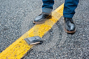 Black wallet with cash is lying lost on the pavement