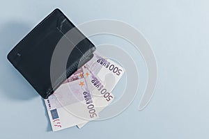 Black wallet and 500 euro bills on gray.