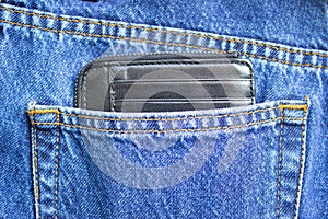 A black wallet for money lies in the back pocket of blue