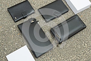 Black wallet purse on pavement. White package with no inscriptions. Leatherette wallet