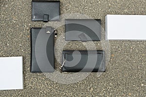 Black wallet purse on pavement. White package with no inscriptions. Leatherette wallet