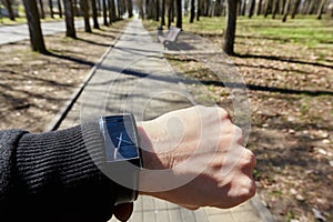 Black watch on a manâ€™s hand on the background of the track in the park