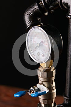 Black water pipes with red taps and a gauge pressure meter