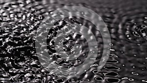 Black water surface monochrome, moving circles and ripples under ultra sound vibrations, abstract background template.