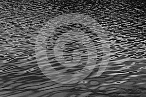 Black water surface with waves. Water ripples. Texture of the water surface