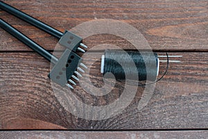 Black waxed threads and a metal hole punch. tools for working with leather on wooden boards