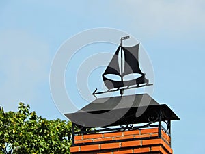 Black weather vane on home roof, Lithuania