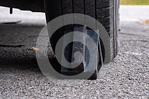 Black wheel chock holding rear rubber tire
