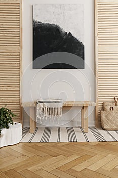Black and white abstract painting above wooden table in natural designed interior